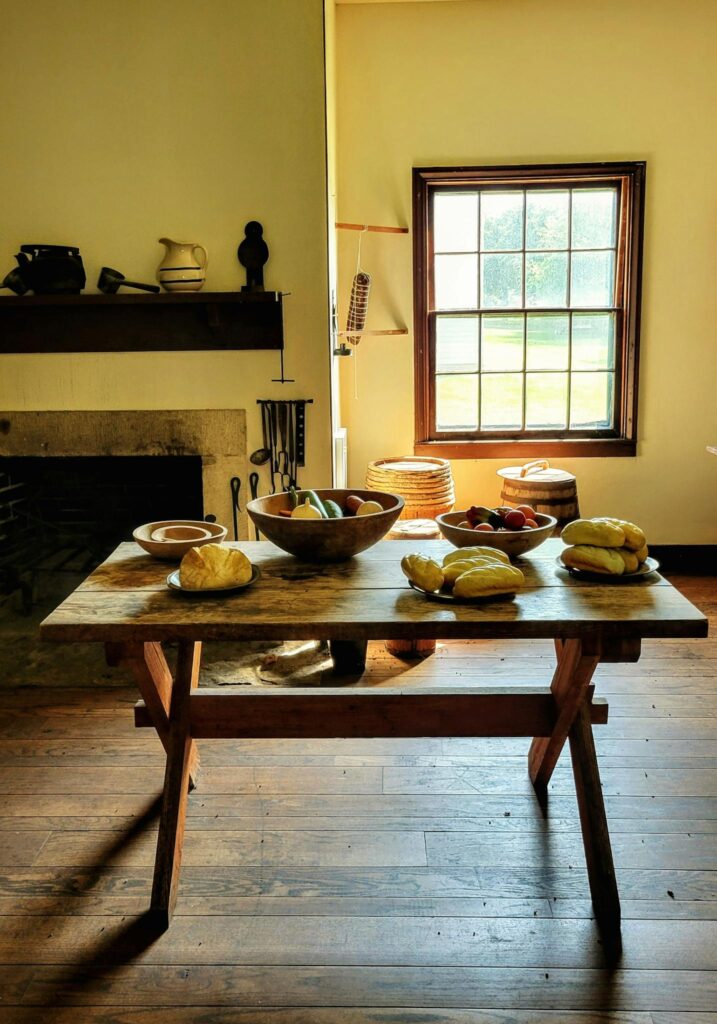 A rustic kitchen setup with a wooden table and fresh produce by a sunlight window.